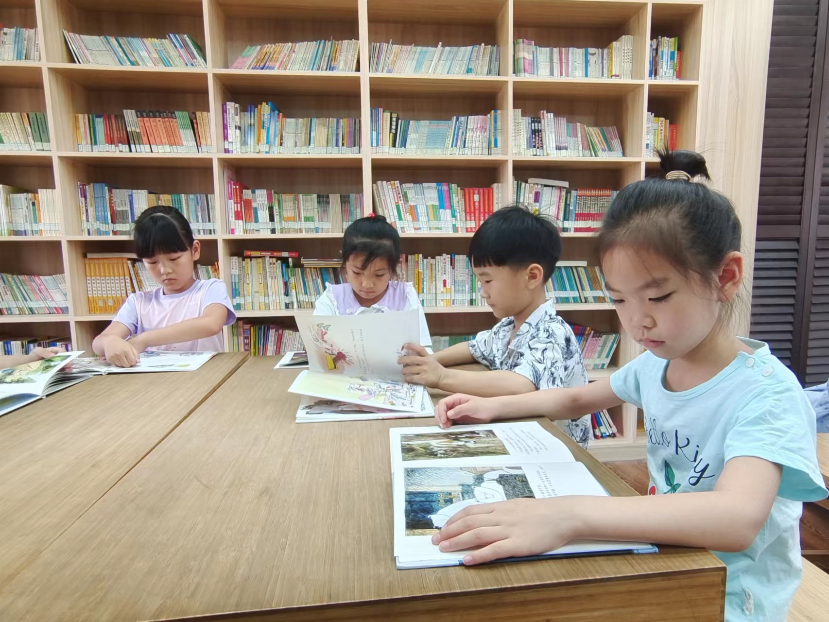 石家庄市新华区：暑期免费托管 精彩“暑”不尽_fororder_在石家庄市和平西路小学，参加暑期托管的小学生在图书馆阅读绘本。