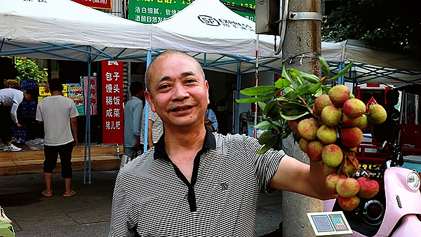 泸州：七月合江果飘香 荔枝成熟开市忙_fororder_果农展示自己出售的荔枝（合江县融媒体中心供图）