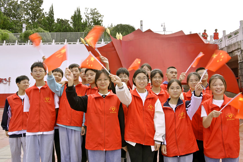 信阳市新县：国庆假期 红色旅游受青睐_fororder_新县红细胞志愿服务队的志愿者挥舞着国旗（焦汉平 摄）