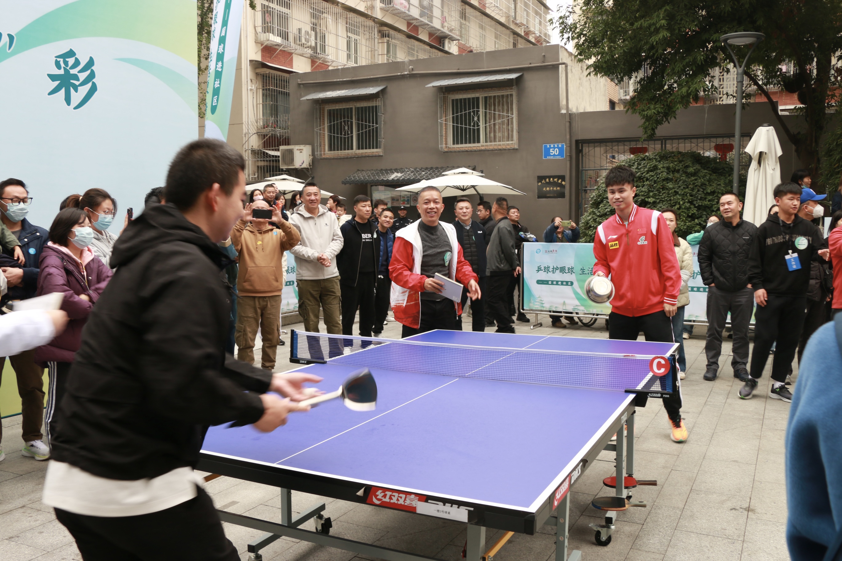乒乓球国手进社区 感受成都赛事名城的万千气象_fororder_周启豪与居民代表用锅铲道具打乒乓球 摄影 杨雯涵