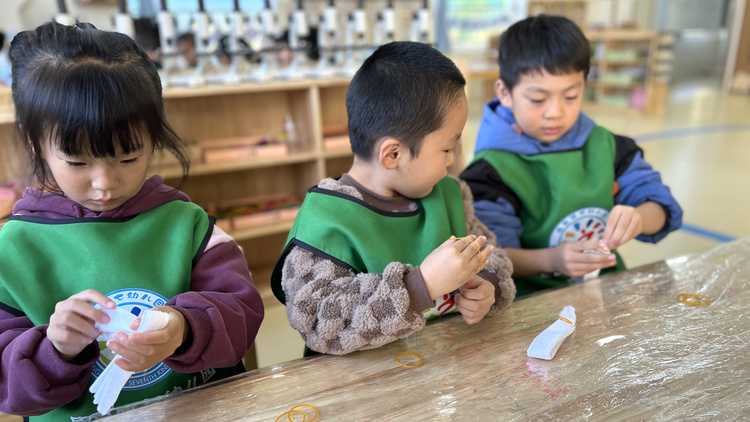 河北唐縣：巧手扎錦繡 感受非遺美_fororder_孩子們用皮筋將折疊好的手絹進行捆綁。紀穎攝