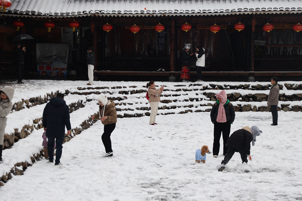 貴州雷山西江千戶苗寨迎來降雪  冬日雪景如畫_fororder_1月22日，貴州省雷山縣西江千戶苗寨迎來2024年第一場降雪。圖為遊客在玩雪。