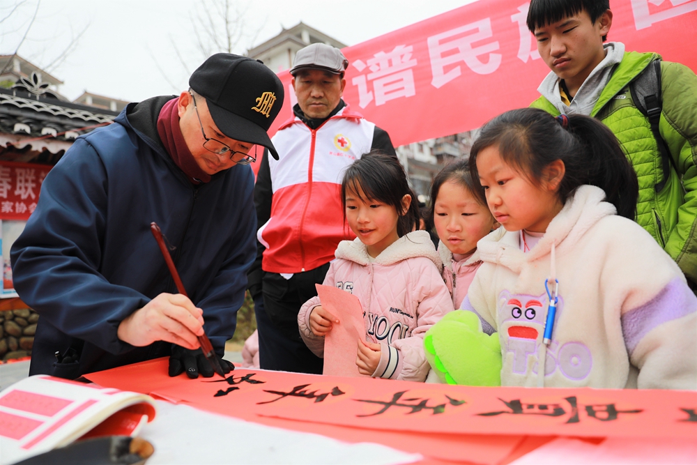 貴州雷山：寫春聯迎新春_fororder_2023年2月2日，在貴州省黔東南苗族侗族自治州雷山縣龍頭街道移民安置點，書法志願者為居民義務寫春聯。