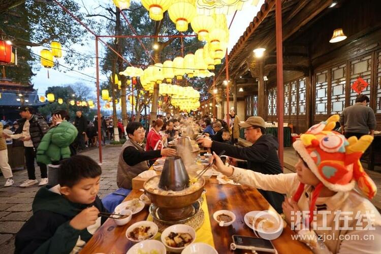 邢然 陆佳钰)2月13日晚,乌镇景区在街巷大摆长街宴,游客边吃着美食,边