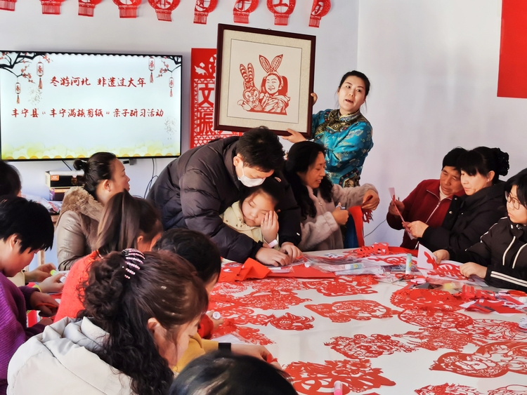 河北丰宁举办“我们的中国梦 文化进万家”亲子非遗研习活动_fororder_县级代表性传承人曹讲解剪纸作品  拍摄白艳宁