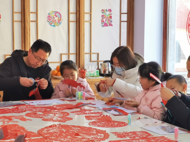 河北丰宁举办“我们的中国梦 文化进万家”亲子非遗研习活动_fororder_亲子互动体验剪纸 拍摄曹艳玲