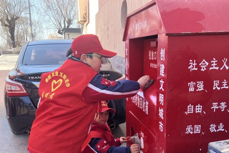 保定徐水区：弘扬雷锋精神 争做文明使者_fororder_小学生们擦拭街头卫生设施。张莉苹摄