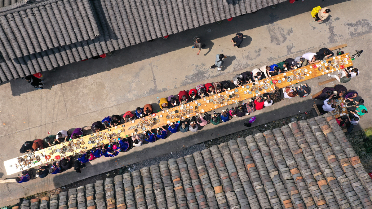 吹蘆笙彈琵琶歌慶“祭薩節” 中外遊客探秘廣西龍勝原生態民族文化_fororder_3月24日,在廣西桂林市龍勝各族自治縣樂江鎮寶贈村,侗族民眾與遊客在共享合攏宴(無人機照片)。 (1).JPG