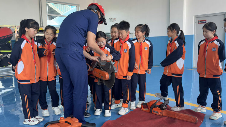 河北唐縣：“紅領巾”走進消防隊 致敬“火焰藍”_fororder_消防員向少先隊員講解器材如何使用