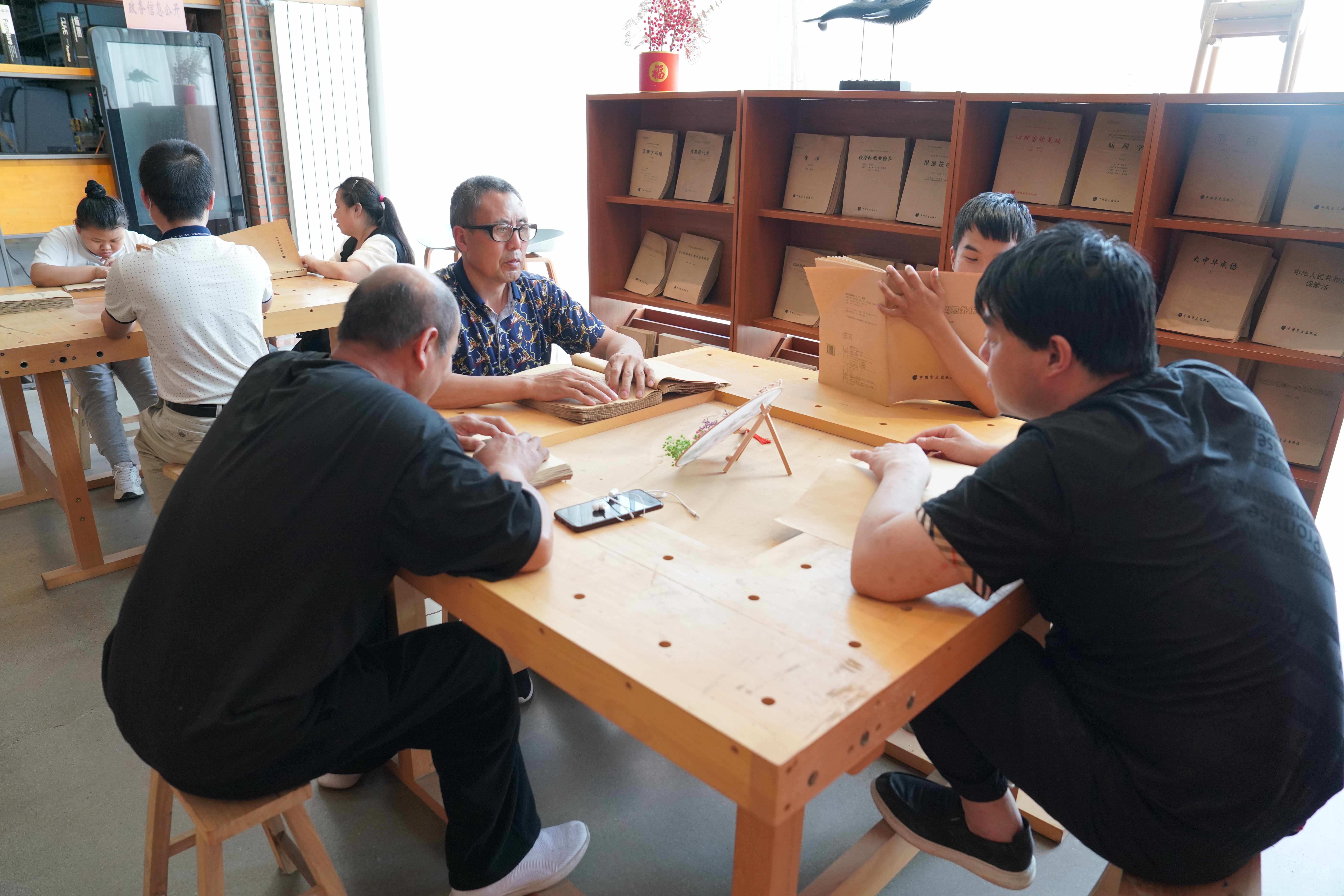 河北清苑:開展“書香潤心 文化助殘”全國助殘日主題活動_fororder_視障人士在專業盲文輔導員的指導下,學習體驗盲文書籍。攝影 王磊