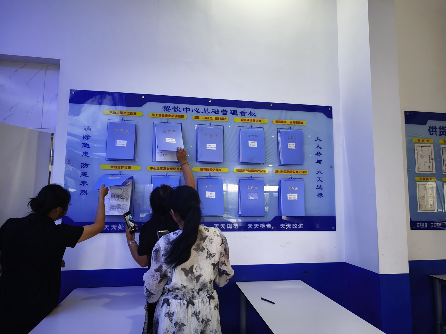 “双争”有我丨保定市满城区组织开展学校食堂观摩学习活动_fororder_参观人员查看学校餐饮台账 摄影 贾林静