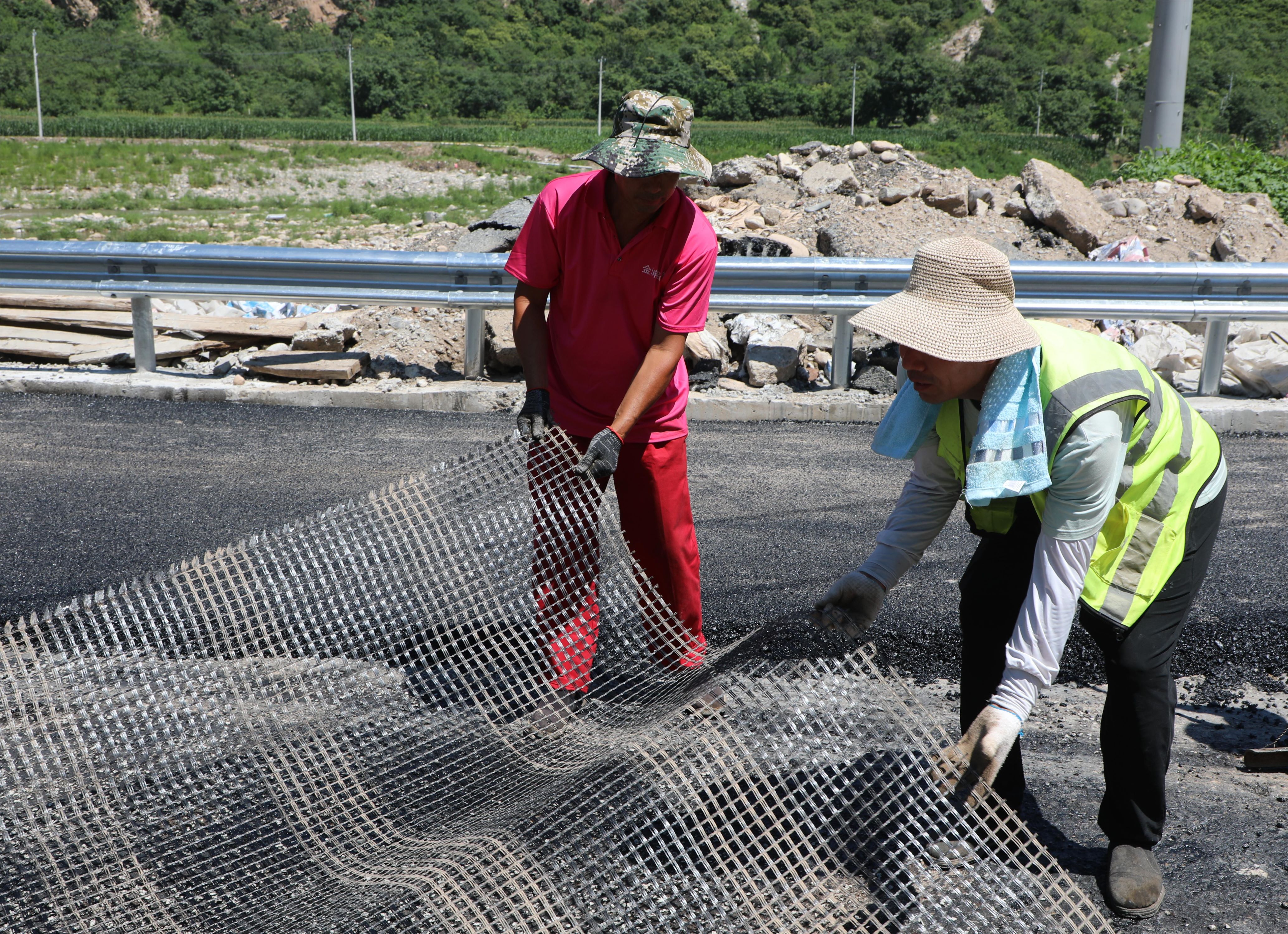 河北涞水：水毁公路恢复重建按下“快进键”_fororder_图为工人正在铺设纤维格栅。（徐梓钰 摄）.JPG