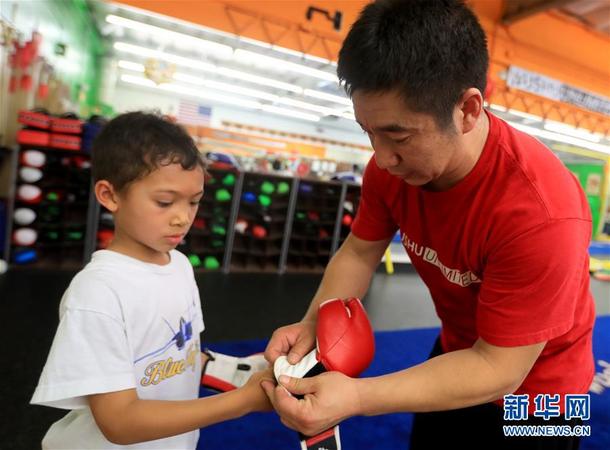 图为王伟(右)帮助小学员带上拳套(5月30日摄)。新华社记者 李颖 摄