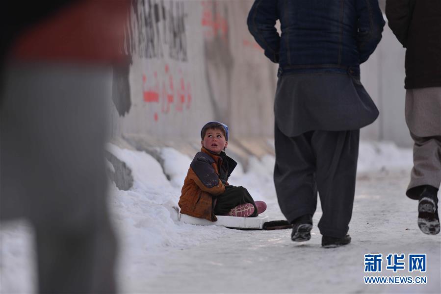 2月6日,在阿富汗首都喀布尔,一名儿童坐在雪地上乞讨