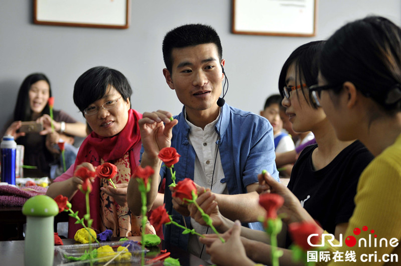 5月14日，山东省郯城县面塑传承人韩红元（中）在“非遗”传承大课上向学员传授面塑花朵的捏制技艺。