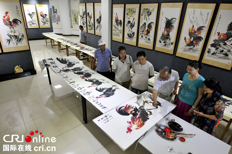山东郯城：七旬老人举办“百鸡画展”庆七一_fororder_6月28日，七旬老人张庆照在“鸡年吉祥庆七一百鸡画展”现场向参观者介绍创作的国画作品《大吉祥》。DSC3695_副本