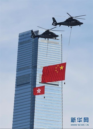 两架分别悬挂中华人民共和国国旗、香港特区区旗的直升机从空中飞过。新华社发(王申 摄)