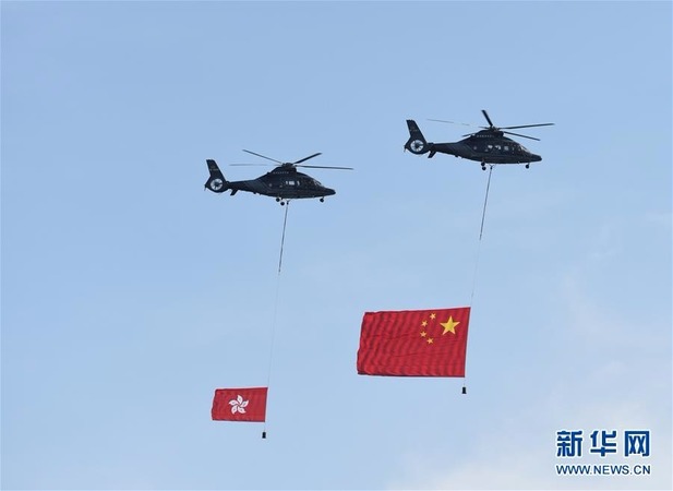 两架分别悬挂中华人民共和国国旗、香港特区区旗的直升机从空中飞过。新华社发(王申 摄)
