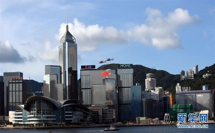 两架分别悬挂中华人民共和国国旗、香港特区区旗的直升机从香港会展中心上空飞过。新华社记者 卢炳辉 摄